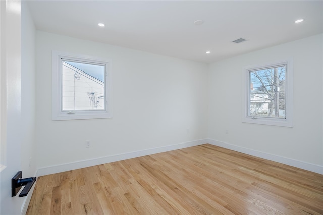 empty room featuring wood finished floors, recessed lighting, baseboards, and visible vents