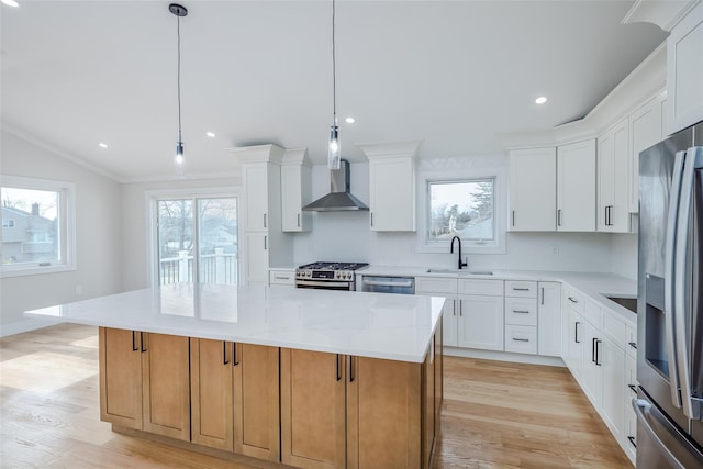 kitchen with stainless steel appliances, a center island, a sink, light wood-style floors, and wall chimney exhaust hood