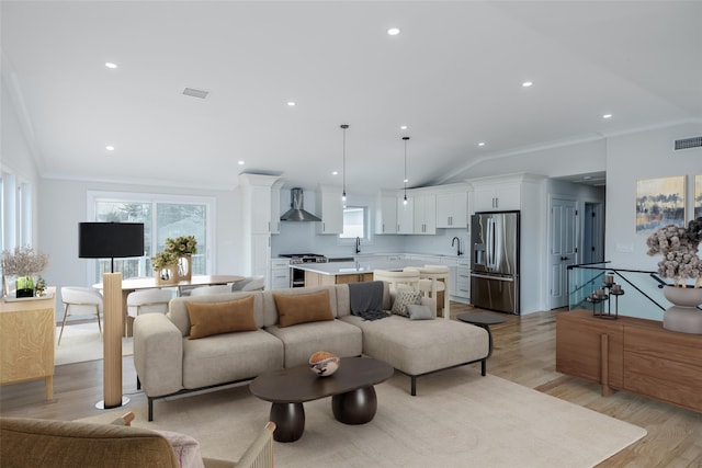 living area featuring plenty of natural light, ornamental molding, light wood-style floors, and visible vents