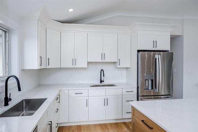 kitchen featuring stainless steel fridge with ice dispenser, white cabinets, and a sink