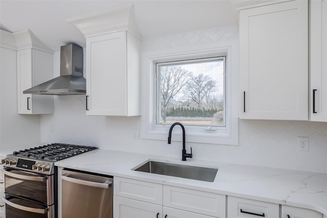 kitchen with a sink, white cabinetry, wall chimney exhaust hood, appliances with stainless steel finishes, and decorative backsplash
