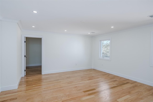 spare room with crown molding, baseboards, and light wood-type flooring