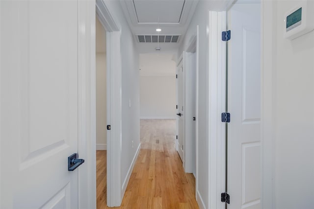 hall featuring baseboards, visible vents, attic access, and light wood finished floors
