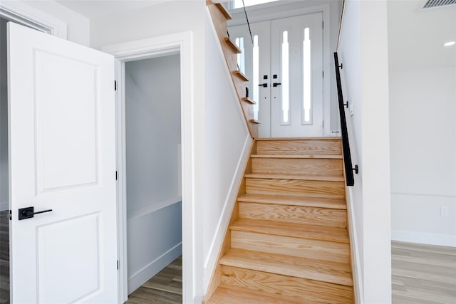 stairway with baseboards, visible vents, and wood finished floors
