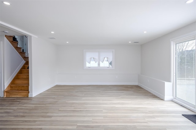 empty room with light wood-style floors, baseboards, stairway, and recessed lighting