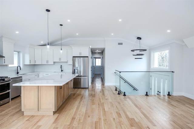 kitchen with a sink, a center island, appliances with stainless steel finishes, and lofted ceiling