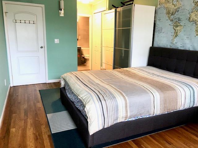 12-31 Robin Ln Unit 52L, Bayside, NY 11360 - bedroom with wood finished floors, baseboards, and connected bathroom