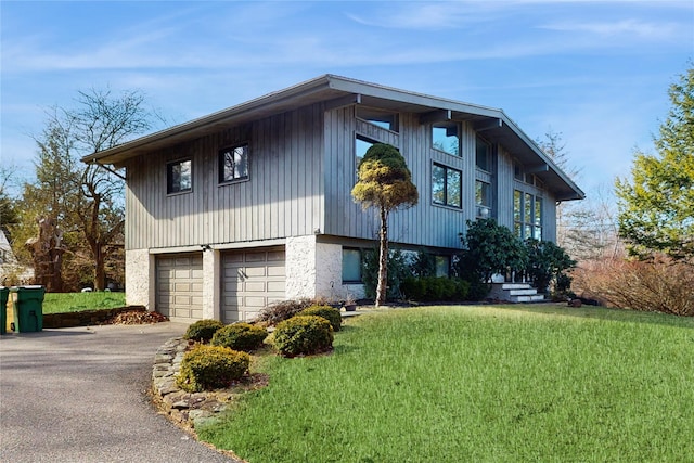 view of front of property with aphalt driveway, a garage, and a front lawn