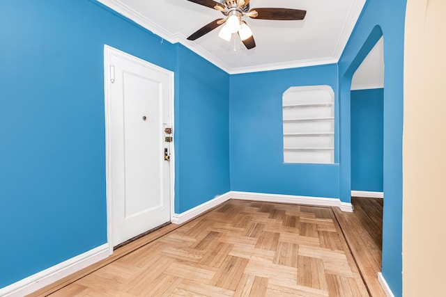 spare room featuring ceiling fan, baseboards, arched walkways, and ornamental molding