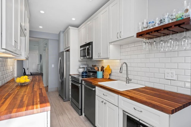 9701 Shore Rd Unit 1O, Brooklyn, NY 11209 - kitchen featuring a sink, butcher block countertops, tasteful backsplash, white cabinets, and appliances with stainless steel finishes