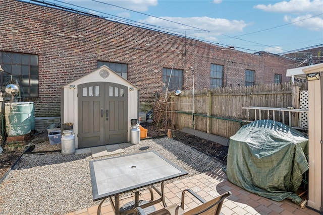 view of patio featuring a storage shed, a grill, fence, and an outdoor structure
