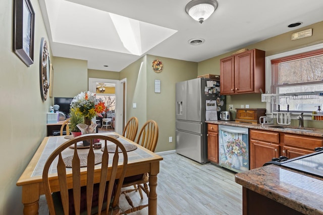 kitchen featuring visible vents, a sink, stone countertops, stainless steel appliances, and light wood finished floors