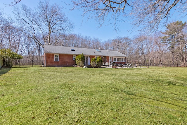 exterior space with fence, a lawn, and brick siding