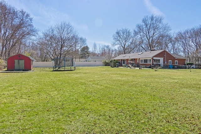 view of yard featuring an outbuilding, a fenced backyard, a storage shed, and a trampoline