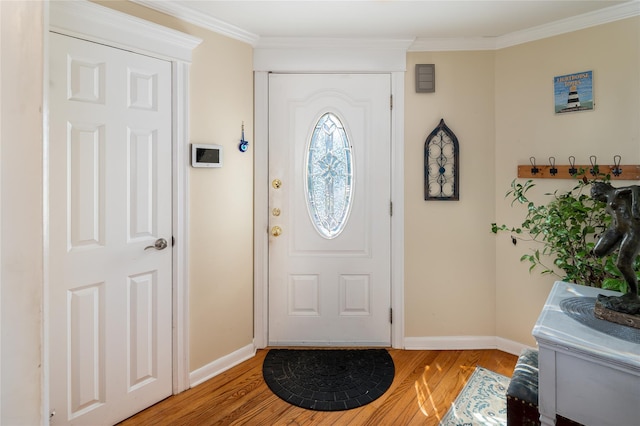 foyer with light wood-style floors, crown molding, and baseboards