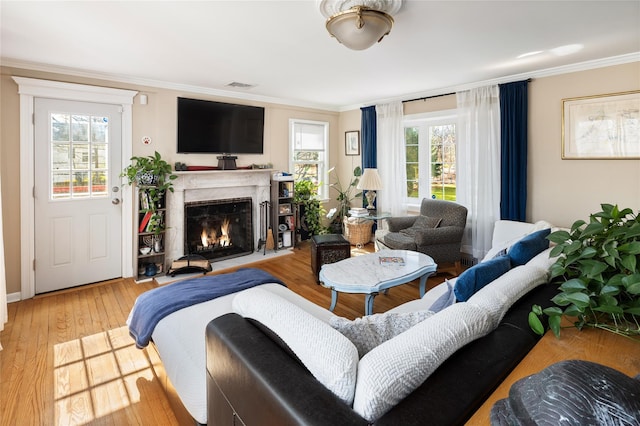 living room with a fireplace with flush hearth, visible vents, and ornamental molding