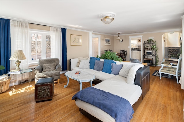 living area with visible vents, light wood-style floors, and crown molding