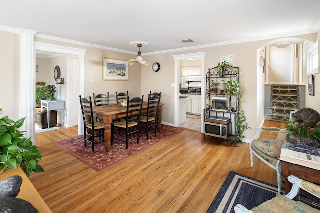 dining space with baseboards, visible vents, ornamental molding, and light wood-type flooring