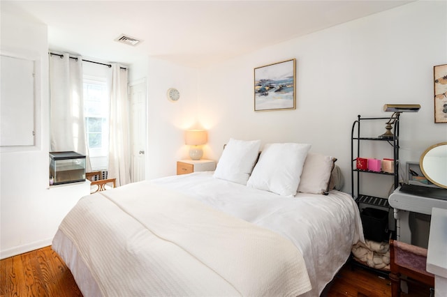bedroom featuring wood finished floors, visible vents, and baseboards