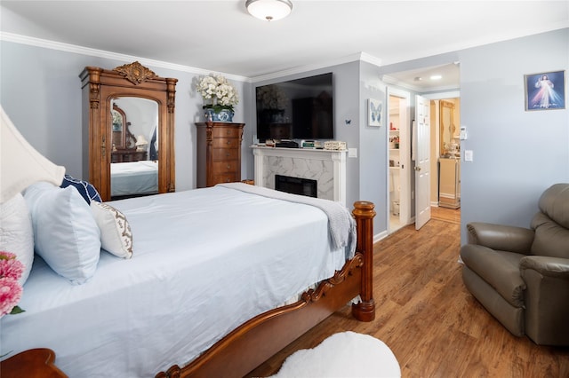 bedroom with ornamental molding, a premium fireplace, wood finished floors, and baseboards