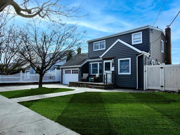 3686 Stokes Ave, Bethpage, NY 11714 - traditional-style house with a front lawn, a gate, fence, an attached garage, and a chimney