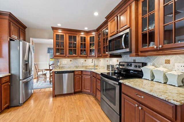 14 Hillside Ave, Saint James, NY 11780 - kitchen with stainless steel appliances, light wood-style flooring, a sink, backsplash, and light stone counters