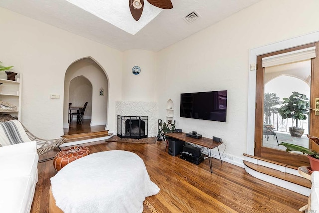 119 Mitchell Ave, Long Beach, NY 11561 - living room featuring visible vents, ceiling fan, wood finished floors, arched walkways, and a fireplace