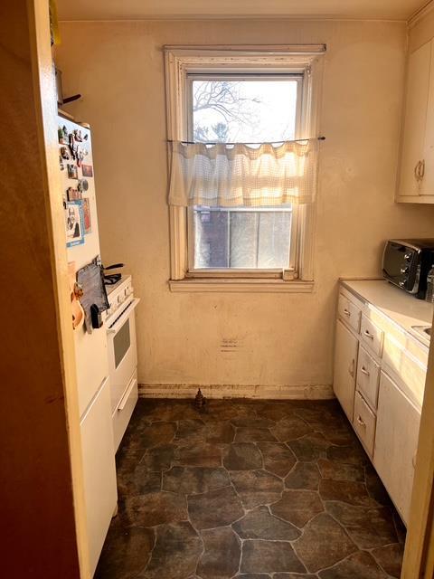 133-25 Blossom Ave, Flushing, NY 11355 - kitchen featuring stone finish flooring, a toaster, light countertops, white appliances, and white cabinetry