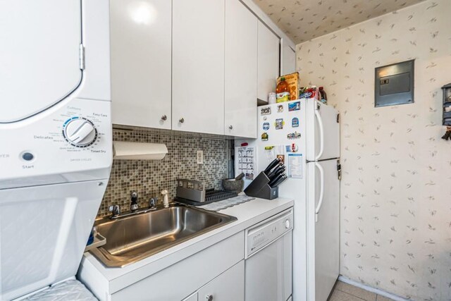 58-30 251st St Unit 2Nd, Little Neck, NY 11362 - kitchen with a sink, stacked washing maching and dryer, white appliances, white cabinets, and wallpapered walls