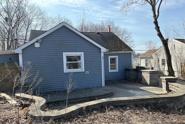 rear view of property featuring roof with shingles