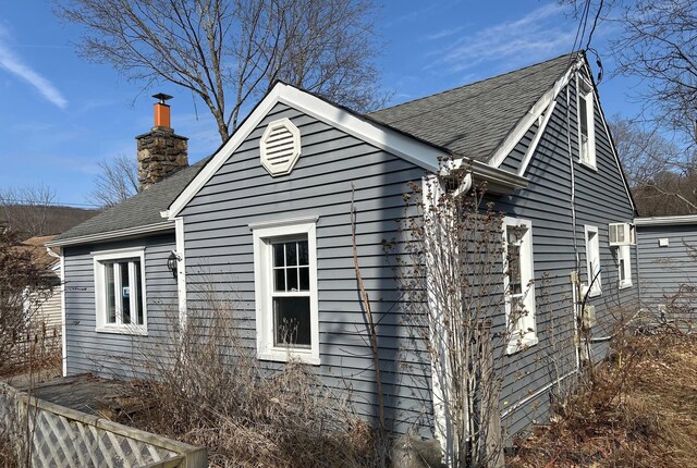 view of property exterior with a chimney and a shingled roof