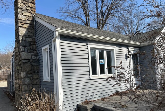 view of home's exterior with a chimney and a shingled roof
