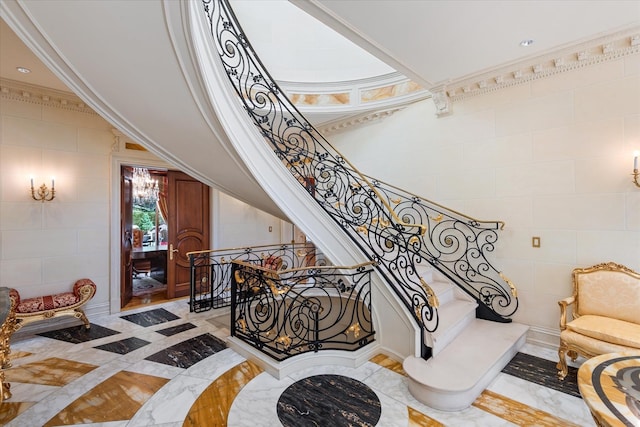 186 Kings Point Rd, Great Neck, NY 11024 - stairway featuring inlaid floor details, marble tiled flooring, tile walls, and ornamental molding