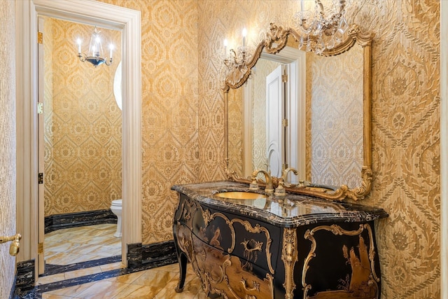 186 Kings Point Rd, Great Neck, NY 11024 - bathroom with inlaid floor details, marble tiled flooring, toilet, vanity, and wallpapered walls