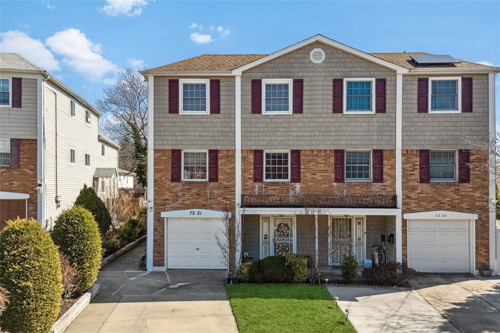 72-21 244th St, Little Neck, NY 11362 - view of property featuring an attached garage, solar panels, brick siding, driveway, and covered porch