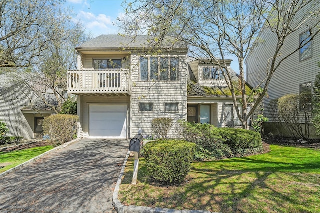 view of front of house with a garage, a balcony, driveway, and a front lawn
