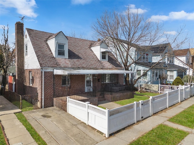 view of front facade featuring brick siding, a chimney, a fenced front yard, and a gate
