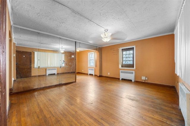 unfurnished living room with a textured ceiling, radiator, and hardwood / wood-style flooring