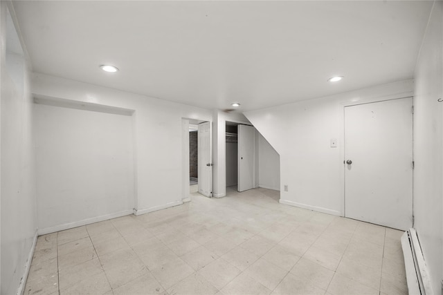 finished basement featuring recessed lighting, light floors, a baseboard heating unit, and baseboards