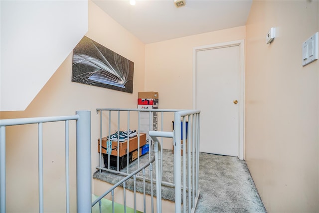 hall featuring an upstairs landing and carpet flooring