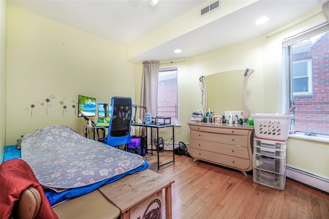 bedroom featuring wood finished floors, recessed lighting, a baseboard heating unit, and visible vents