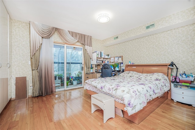 bedroom with wallpapered walls, wood finished floors, access to outside, and visible vents