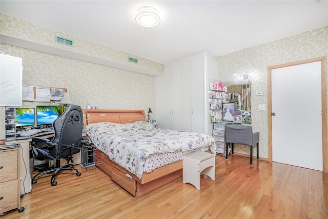 bedroom with wallpapered walls, visible vents, and light wood-style flooring