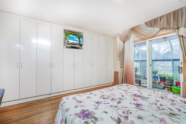bedroom with light wood-style floors and access to outside