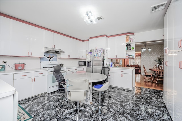 kitchen with visible vents, white gas stove, under cabinet range hood, white cabinetry, and stainless steel fridge with ice dispenser