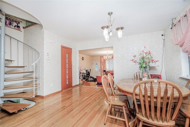 dining room featuring stairs, wood finished floors, baseboards, and a chandelier