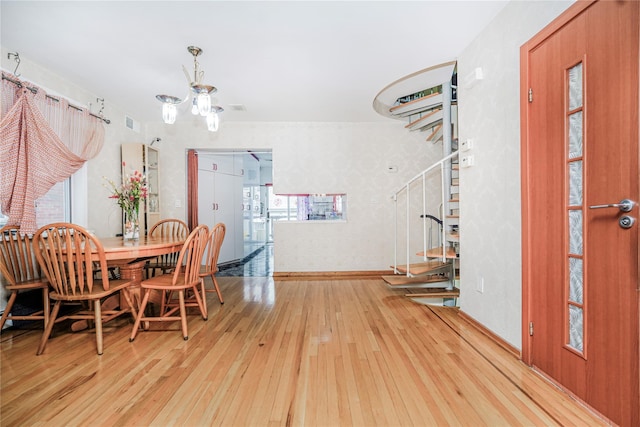 dining space with hardwood / wood-style floors, visible vents, and an inviting chandelier