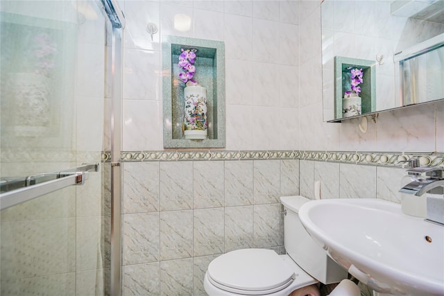 full bathroom with a shower stall, tile walls, toilet, and a sink