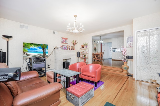living room featuring hardwood / wood-style floors, a fireplace, visible vents, and a chandelier