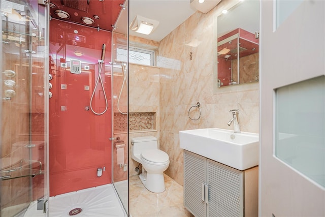 bathroom with toilet, vanity, a shower stall, tile patterned flooring, and tile walls